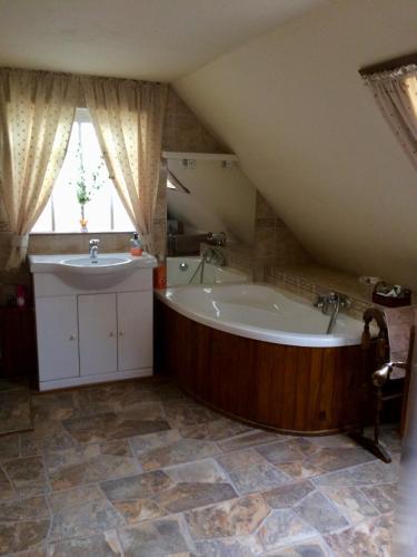 La salle de bains est pourvue d'une grande baignoire et d'un lavabo. dans l'établissement La Petite Maison, Vignols, à Vignols