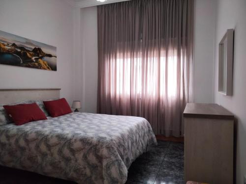 sypialnia z łóżkiem z czerwonymi poduszkami i oknem w obiekcie APARTAMENTOS La PEÑA A w mieście La Guancha