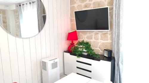 a living room with a tv on a wall at Le Petit Paradis in Brive-la-Gaillarde