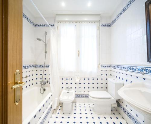 a bathroom with a white toilet and a tub and a sink at Miramar. Basquenjoy in Hondarribia