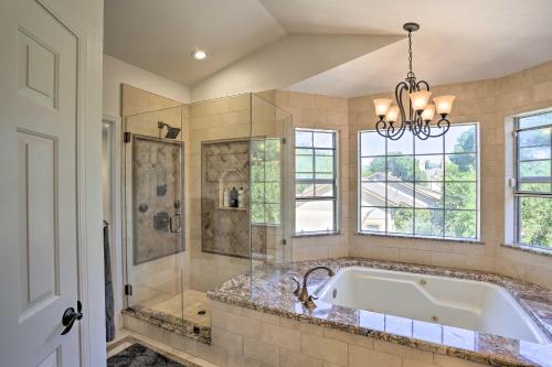 a bathroom with a tub and a shower and a chandelier at Redding Getaway with Hot Tub and Outdoor Kitchen! in Redding