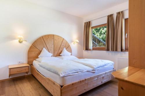 - une chambre avec un grand lit et une tête de lit en bois dans l'établissement Ferienparadies Sabina Joch, à Alpe di Siusi