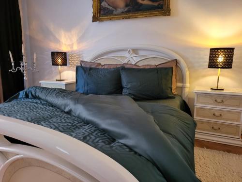 a bedroom with a large bed with two lamps at Apartments Vila White House in Pančevo