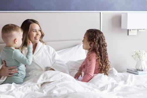 a woman and two children sitting on a bed at Four Seasons St. Louis in Saint Louis