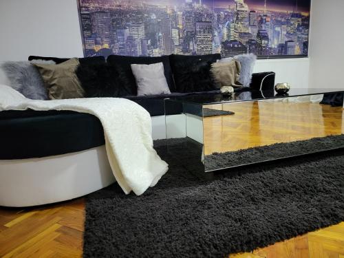 a living room with a black couch and a glass table at Apartments & Pool Villa White House in Pančevo