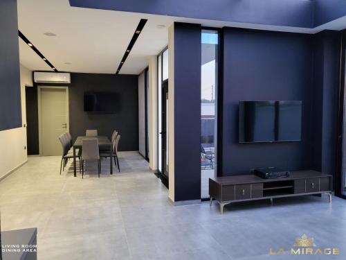 a dining room with a table and a tv on a wall at La Mirage Villa in Rrushkull
