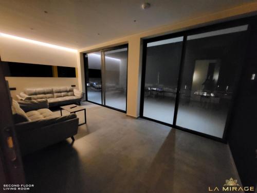 a living room with a couch and glass windows at La Mirage Villa in Rrushkull