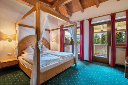 a bedroom with a canopy bed in a room with windows at Ferienparadies Sabina Föhre in Alpe di Siusi