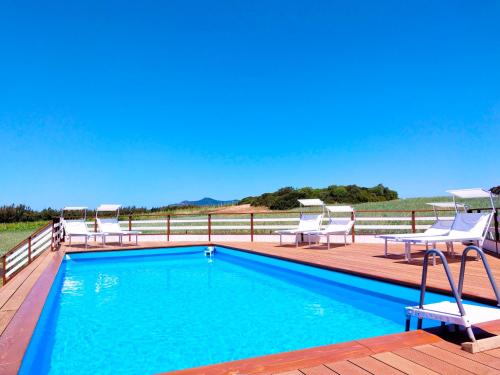 uma piscina com cadeiras e um deque de madeira em Podere Cala Viola em Porto Conte