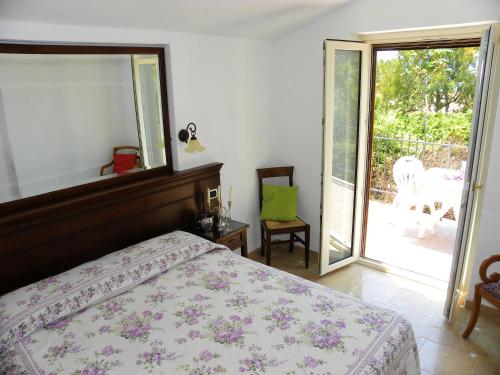 um quarto com uma cama e uma porta de vidro deslizante em 2 bedrooms house at Maratea 500 m away from the beach with sea view enclosed garden and wifi em Maratea