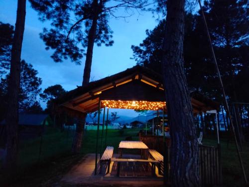 a gazebo with a picnic table and a tree at Odyssey Stays Umbir, Umiam Lake in Mawlyngkhung