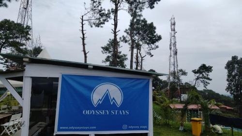 a sign in front of a building with trees at Odyssey Stays Umbir, Umiam Lake in Mawlyngkhung