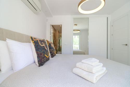a bedroom with a white bed with towels on it at Playa Real Luxury Apartment in Marbella