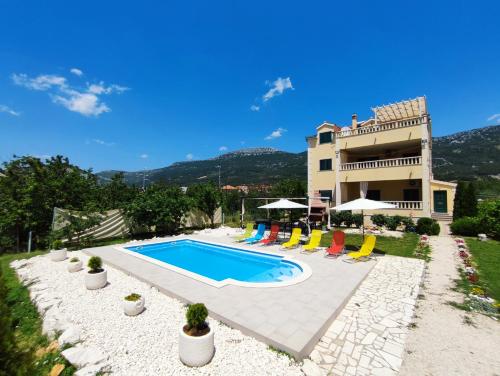 una villa con piscina di fronte a una casa di Apartments Maris a Kaštela (Castelli)