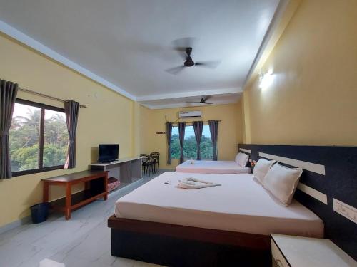 a bedroom with two beds and a desk and a tv at Blue Stone Hotel & Restaurant Mandarmani in Mandarmoni