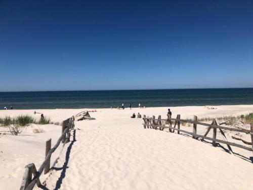 a sandy beach with a wooden pathway to the ocean at Domki nad morzem Sasino Mojo Miodno Checz in Sasino