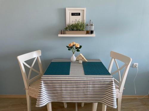 a dining room table with two chairs and a vase of flowers at Studio B28 Sunny Island Chernomorez in Chernomorets