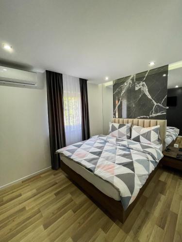 a bedroom with a large bed with a checkered blanket at Apartmani Mila in Laktaši