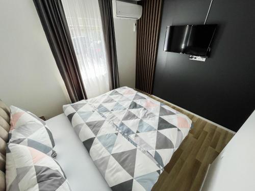 a bed with a comforter and a television in a room at Apartmani Mila in Laktaši