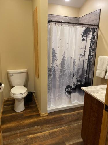 y baño con aseo y cortina de ducha. en Rough Cut Lodge, en Gaines