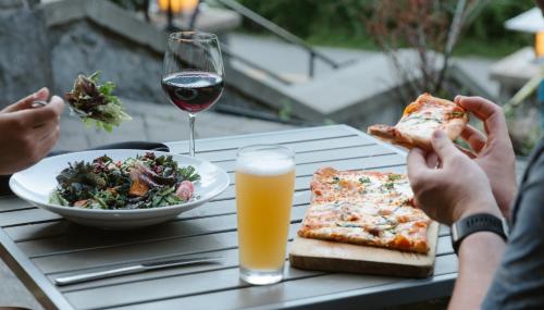a group of people sitting at a table eating pizza and a salad at Nita Lake Lodge in Whistler