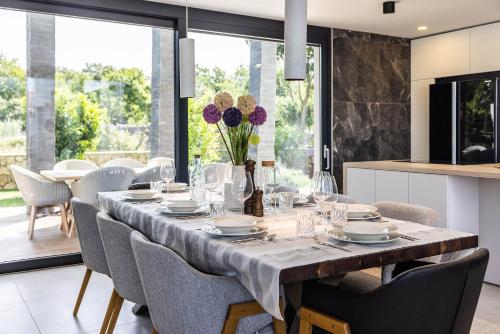 a dining room with a table with chairs and a kitchen at FIRST RESIDENCE Villa Eternity in Linardići