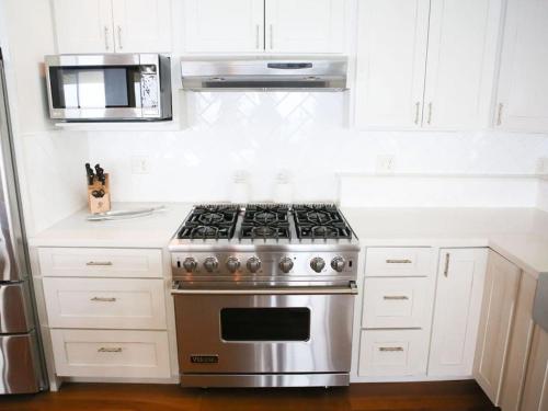 a stainless steel stove in a kitchen with white cabinets at Waimea Bay Luxury Estate Views & Hot Tub in Haleiwa