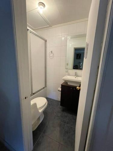 een badkamer met een toilet, een wastafel en een spiegel bij Hostal Nomade in Constitución