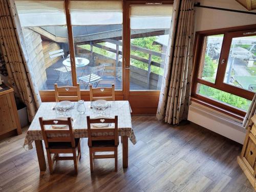 une salle à manger avec une table, des chaises et des fenêtres dans l'établissement Appartement lumineux avec terrasse, parking et WiFi aux Gets - FR-1-598-51, aux Gets