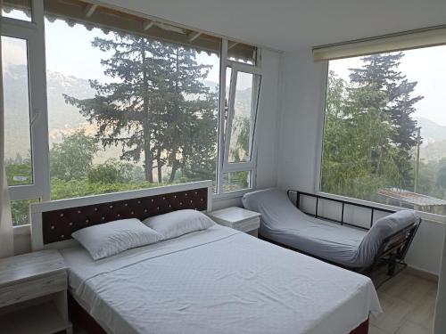 a bedroom with a bed and a bench and windows at TOKGÖZ HOTEL RESTAURANT in Ulupinar