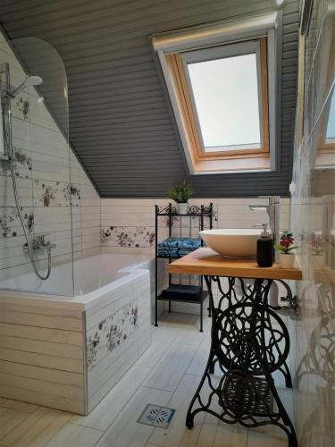 a bathroom with a tub and a sink and a window at Nárcisz Vendégház 2 in Mezőkövesd