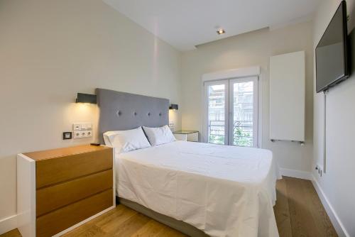 a white bedroom with a bed and a television at Apartamento Velazquez vistas in Madrid