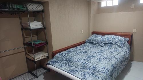ein Schlafzimmer mit einem Bett mit einer blau-weißen Bettdecke in der Unterkunft San Marino grupos familiares o amigos in San Francisco Tlalnepantla