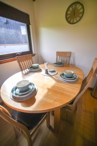 a wooden table with four chairs and a clock on the wall at Glenview Chalet Park in Inverness