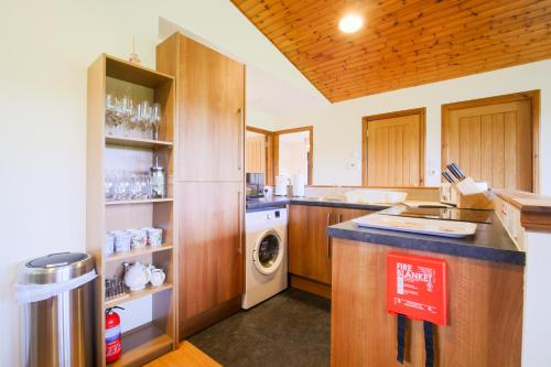 a kitchen with wooden cabinets and a washer and dryer at Glenview Chalet Park in Inverness