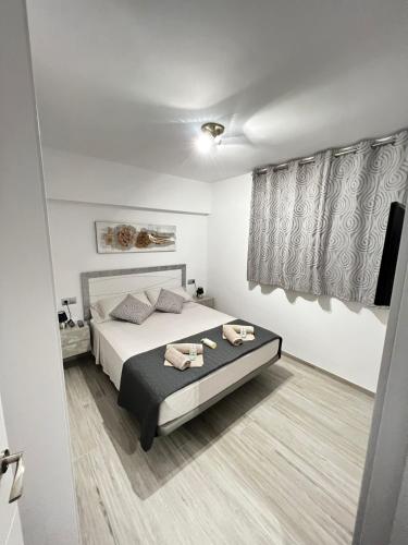 a white bedroom with a bed and a window at Apartamento el Cid in Calpe