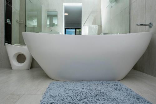 La salle de bains est pourvue d'une grande baignoire blanche et de toilettes. dans l'établissement Cap du Mont, à Bloubergstrand