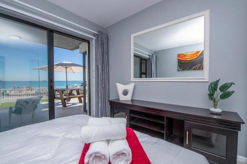 a bedroom with a bed and a desk with a mirror at Cap du Mont in Bloubergstrand