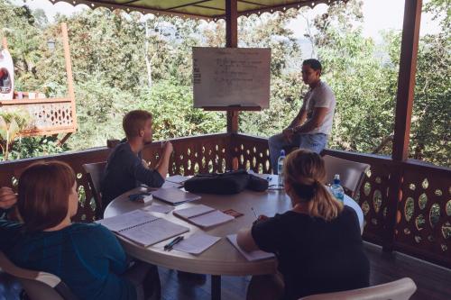a group of people sitting around a table on a porch at Spanish by the River - Turrialba in Turrialba