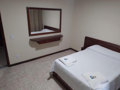 Hotel Recanto da Itália في نوفا فريبورغو: غرفة نوم مع سرير ومرآة على الحائط