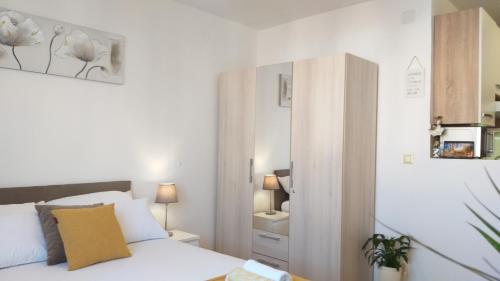 ein weißes Schlafzimmer mit einem Bett und einem Spiegel in der Unterkunft Apartments Plokite in Split