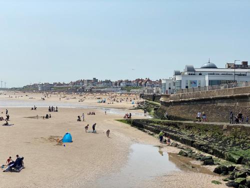 un grupo de personas en una playa cerca de un cuerpo de agua en Windmill Guest House en Bridlington