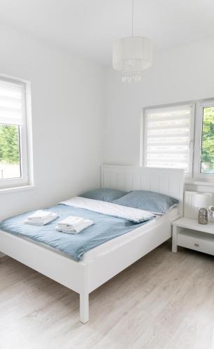 a white bedroom with a bed in a room with windows at Apartamenty Zdrój in Polanica-Zdrój