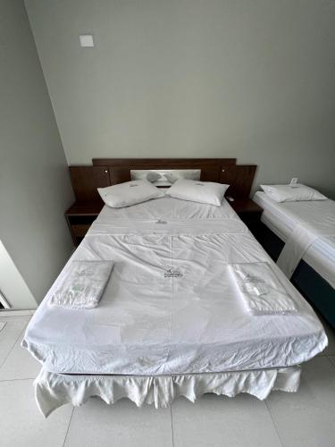 Elle comprend un grand lit blanc avec des draps et des oreillers blancs. dans l'établissement Pinheiro Flat Hotel, à Ibiapina
