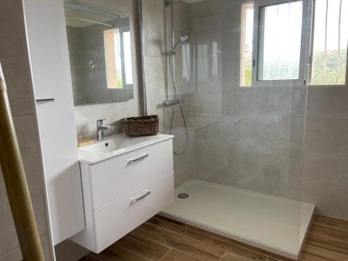 La salle de bains blanche est pourvue d'une douche et d'un lavabo. dans l'établissement Oustaou di Ercole, à Bormes-les-Mimosas