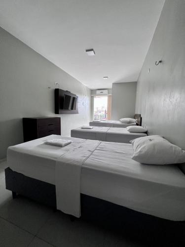 a room with three beds and a tv on the wall at Pinheiro Flat Hotel in Ibiapina