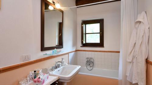 een badkamer met een wastafel, een spiegel en een bad bij Villa Nocciola Il Poderone in Roccalbegna