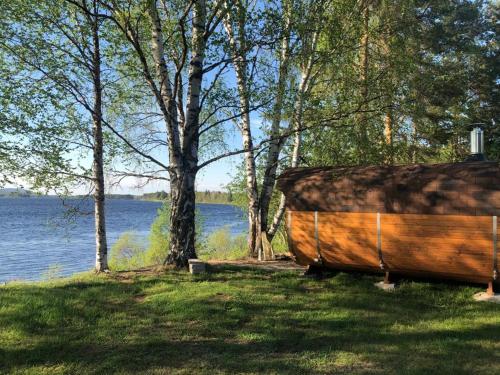 un barco de madera sentado en el césped junto a un lago en Napapiirin Eräkartano en Pello