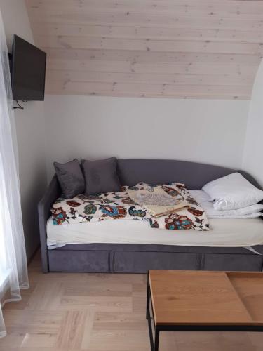 a bed sitting in a room with a table at Kotedžas poilsiui in Palanga