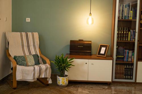 a living room with a chair and a book shelf at Blossom Apartment Kos in Ampavris